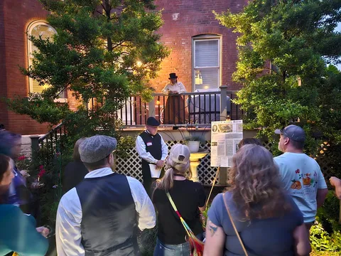 An interpreter reads from a balcony as a group listens